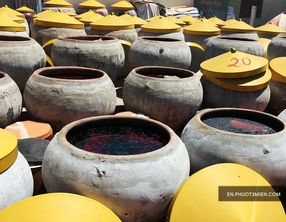 This image shows three dozen large clay jars full of fish sauce, which is fermenting in the Vietnam sun.